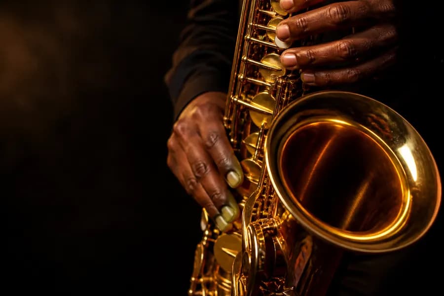 A brass saxophone being played, warm light catching the bell and keys
